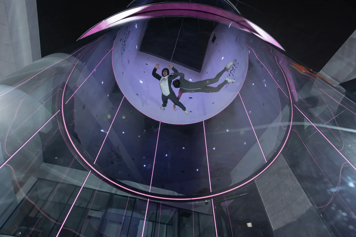 The TT45 Pro wind tunnel in action at the WindAlps facility in France. The fully transparent glass flight chamber offers optimal visibility as an instructor guides a novice flyer through the airflow.