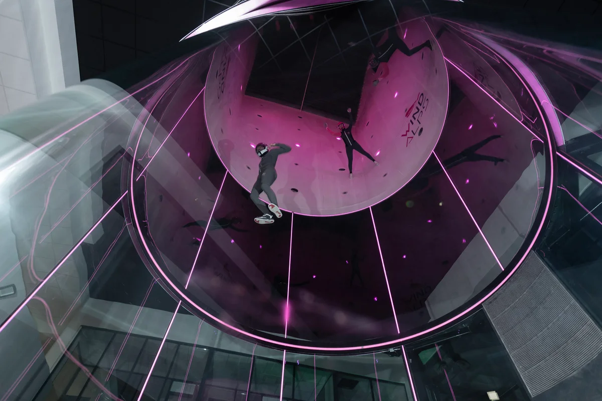 فرانس میں ونڈ ایلپس (Wind Alps) کی تنصیب پر TT45 PRO فلائٹ چیمبر کے اندر اوپر کی طرف عمودی منظر۔ تین فلائرز TunnelTech کی مکمل گول ملٹی لیئر گلاس کی دیواروں کے درمیان ہیڈ اَپ (head-up) مشق کر رہے ہیں۔ گلابی روشنی سے روشن یہ 4.5 میٹر ProFly سسٹم جدید فری فلائی (freefly) کے لیے درکار تیز رفتار ایئر فلو فرا ہم کرتا ہے۔