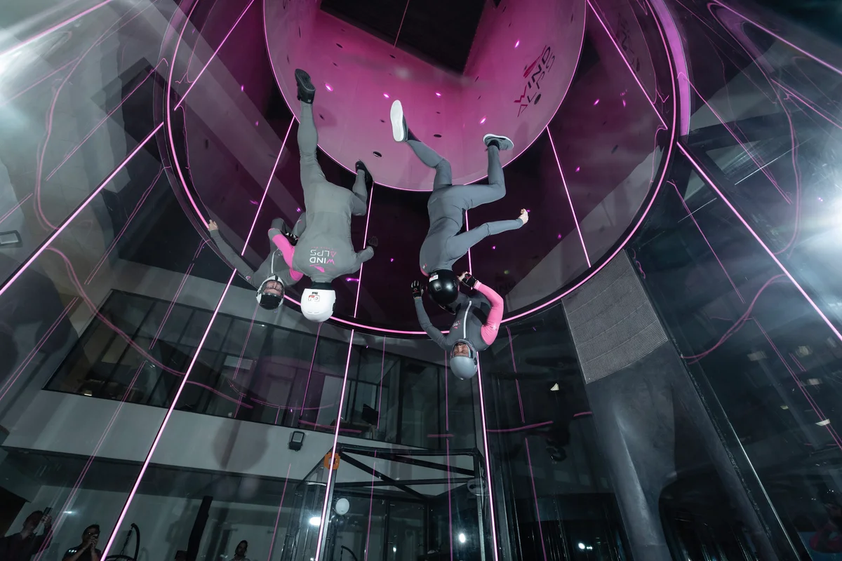 High-Performance-Training bei WindAlps: Das Instruktoren-Team feilt im TT45 PRO an seiner Head-Down-Technik. Der gleichmäßige Luftstrom ermöglicht präzises vertikales Fliegen, während die dynamische Beleuchtung die Glas-Flugkammer in Szene setzt.